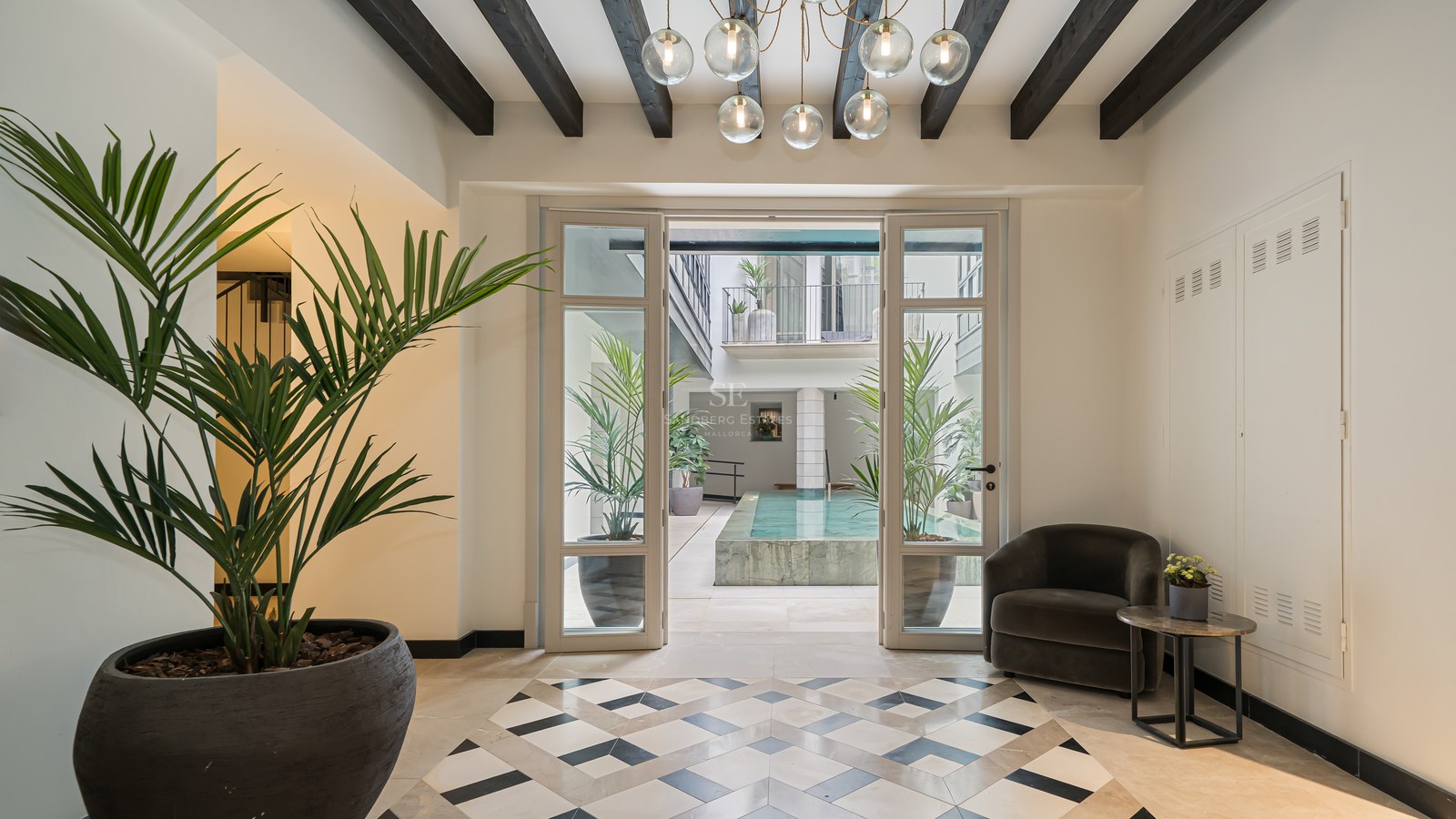 Luxury entrance hall with geometric floor tiles leading to a sunlit internal courtyard and plunge pool.