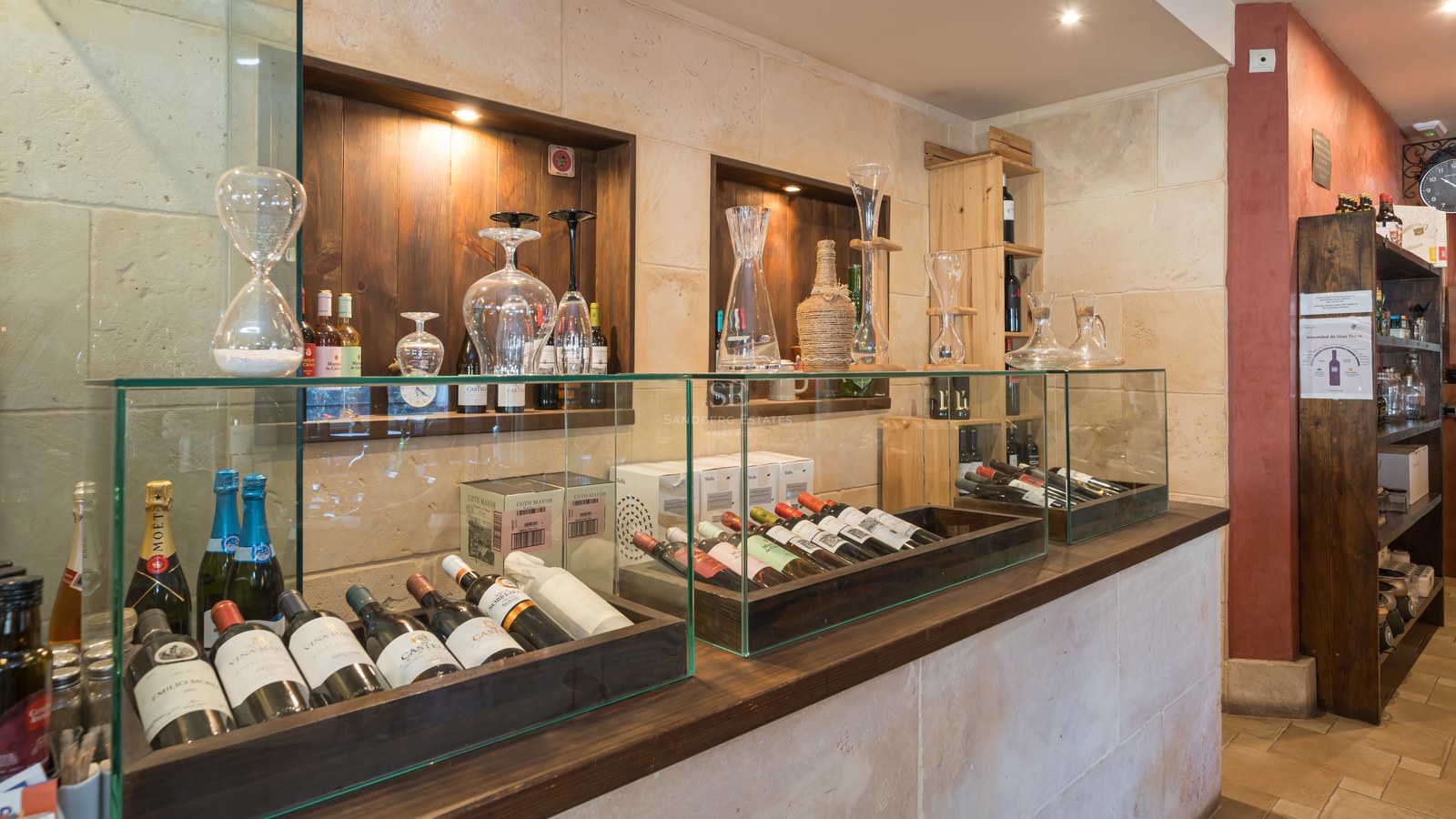 Interior de una bodega de lujo con vitrinas de cristal, paredes de piedra natural y estanterías de madera oscura.