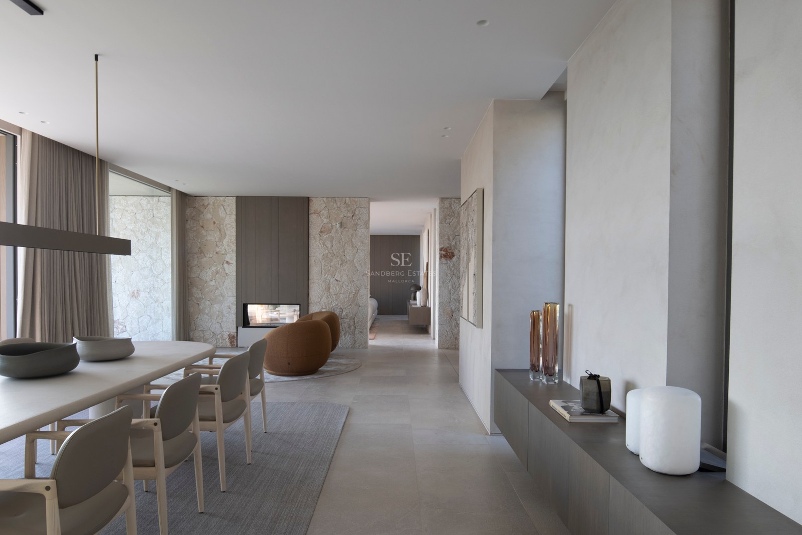 Salle à manger contemporaine avec mur en pierre naturelle, cheminée moderne et sol en grès cérame grand format.