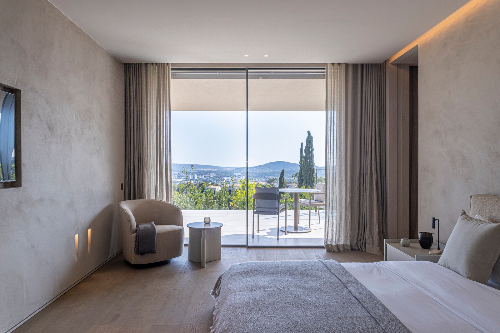 Chambre moderne avec parquet en chêne ouvrant sur une terrasse privée offrant une vue panoramique sur les collines.