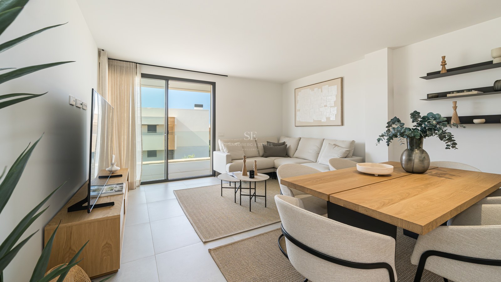 Contemporary living and dining room featuring a cream sofa, oak furniture, and floor-to-ceiling glass doors to a terrace.