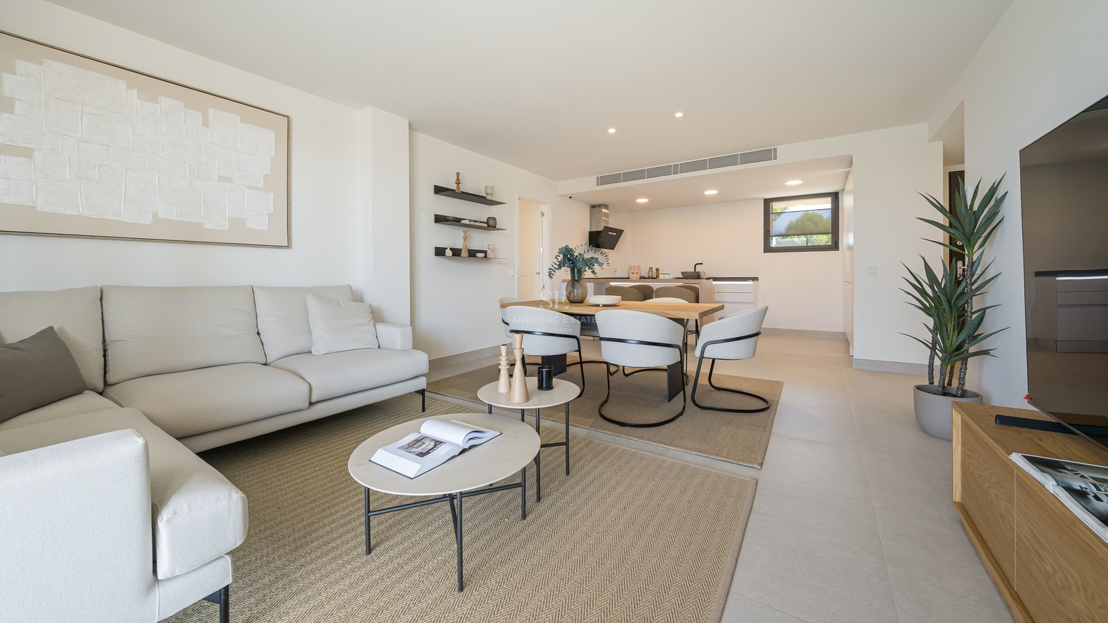Bright open-plan living room with cream sofa, round coffee tables, and dining area in neutral tones.