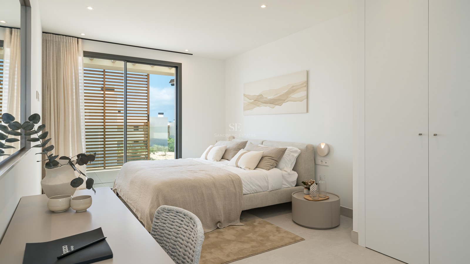 Bright contemporary bedroom with a double bed, white wardrobes, and sliding glass doors opening to a sunlit terrace.