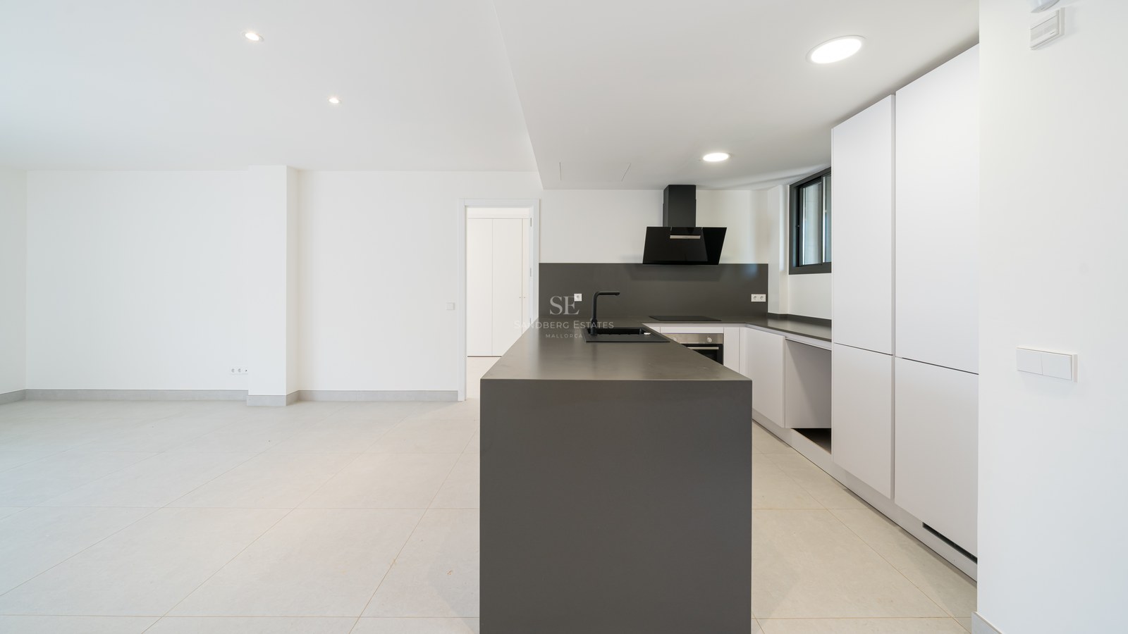 Contemporary kitchen featuring a dark grey central island, white cabinetry, and matte black fixtures in a bright space.
