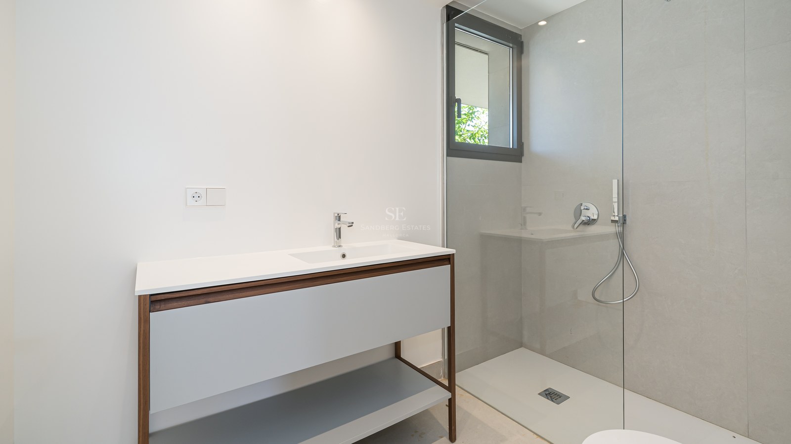 Modern bathroom featuring a wood-framed vanity, glass shower partition, and large-format grey wall tiles.