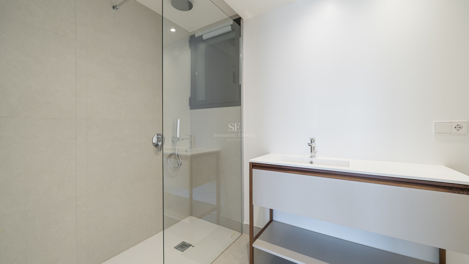 Modern bathroom featuring a glass-enclosed walk-in shower with beige tiles and a sleek white and wood vanity.