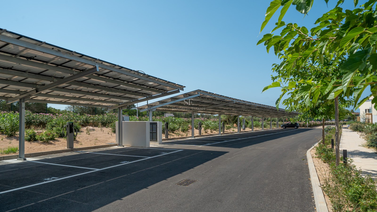 Modern outdoor parking area featuring solar panel roof structures and electric vehicle charging stations under a clear sky.