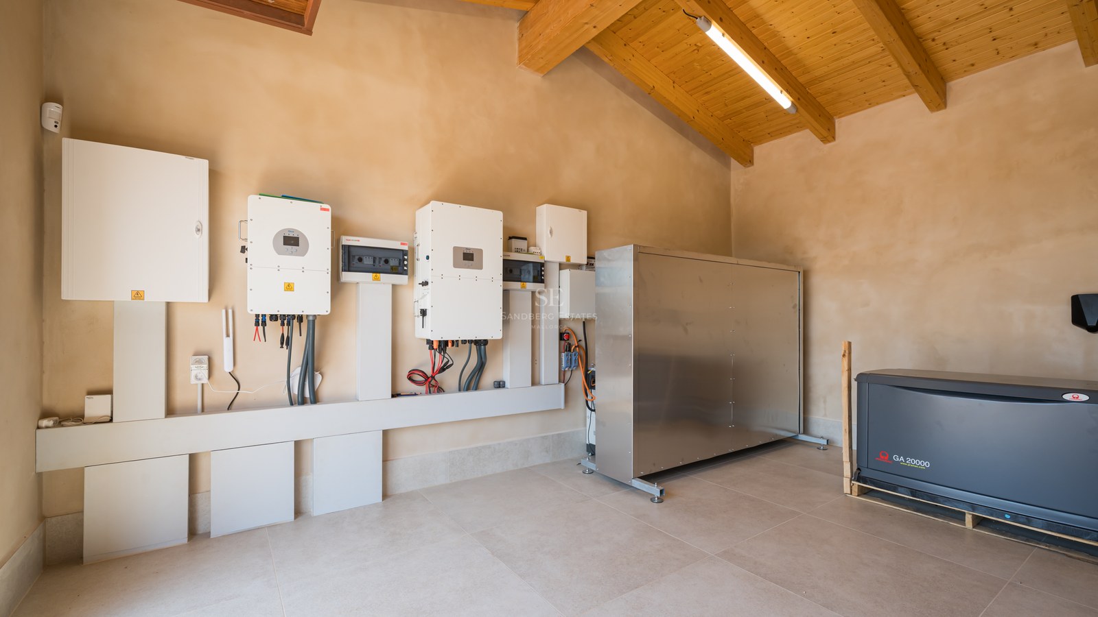 Local technique avec onduleurs solaires, tableaux électriques et générateur de secours sous plafond boisé.