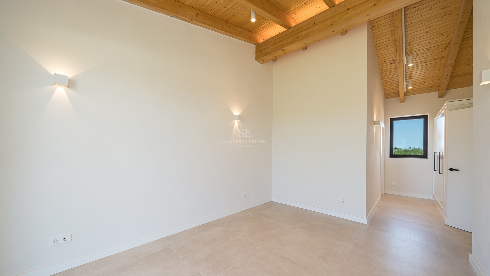 Chambre épurée avec plafond voûté en bois, sol en grès cérame beige et murs blancs avec appliques murales.