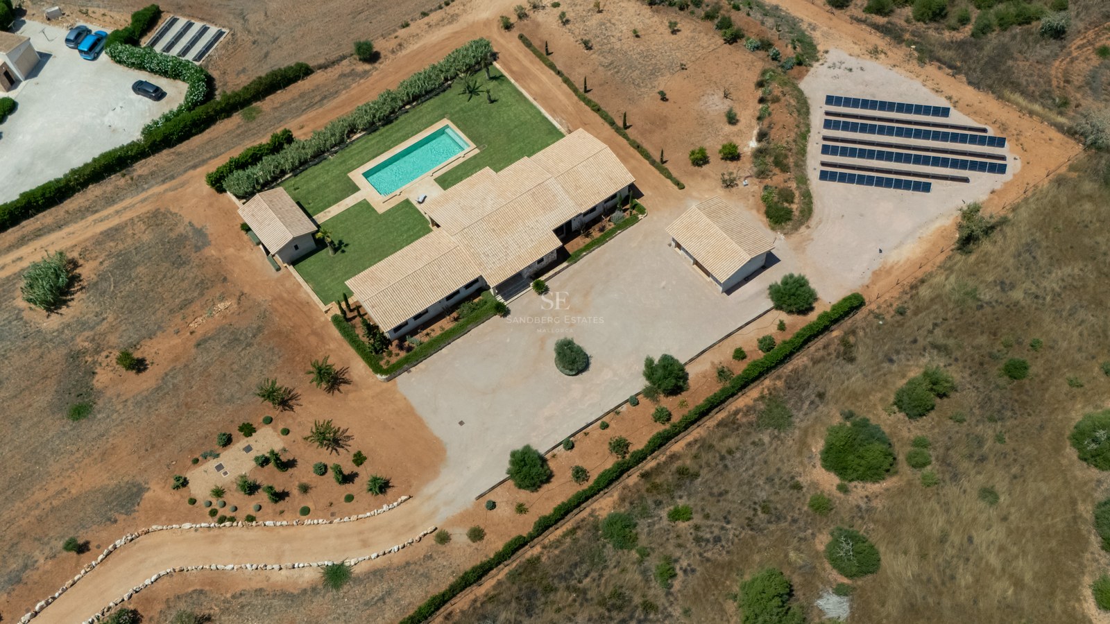 Vue d'en haut d'une villa avec piscine, panneaux solaires et jardins sur un vaste terrain privé.