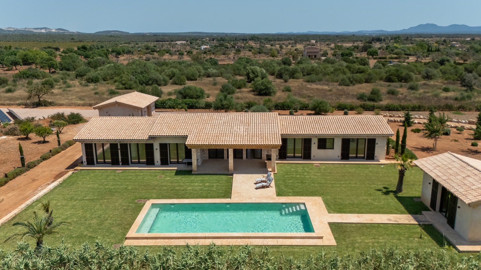 Vue aérienne d'une villa de luxe avec piscine, grande pelouse et environnement rural méditerranéen.