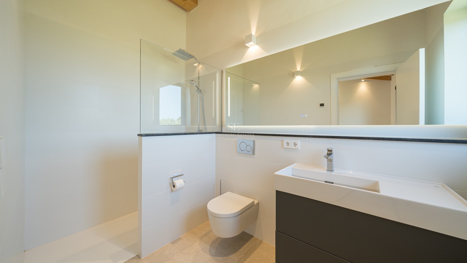 Salle de bains contemporaine avec douche vitrée, toilettes suspendues et grand miroir rétroéclairé.