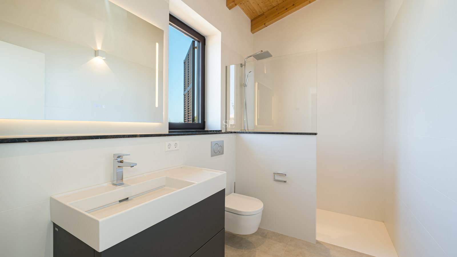 Salle de bains moderne blanche avec douche à l'italienne, meuble vasque suspendu, miroir LED et poutres en bois.