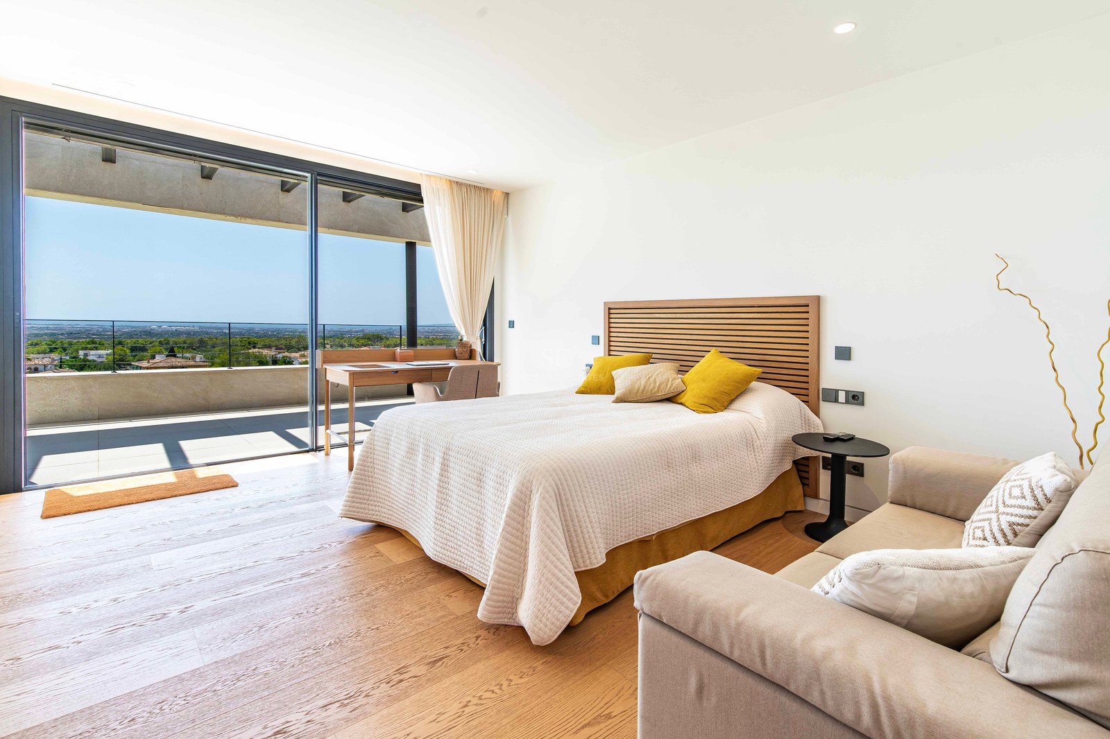 Modern master bedroom featuring oak floors, a double bed, integrated desk, and large glass doors opening to a terrace.