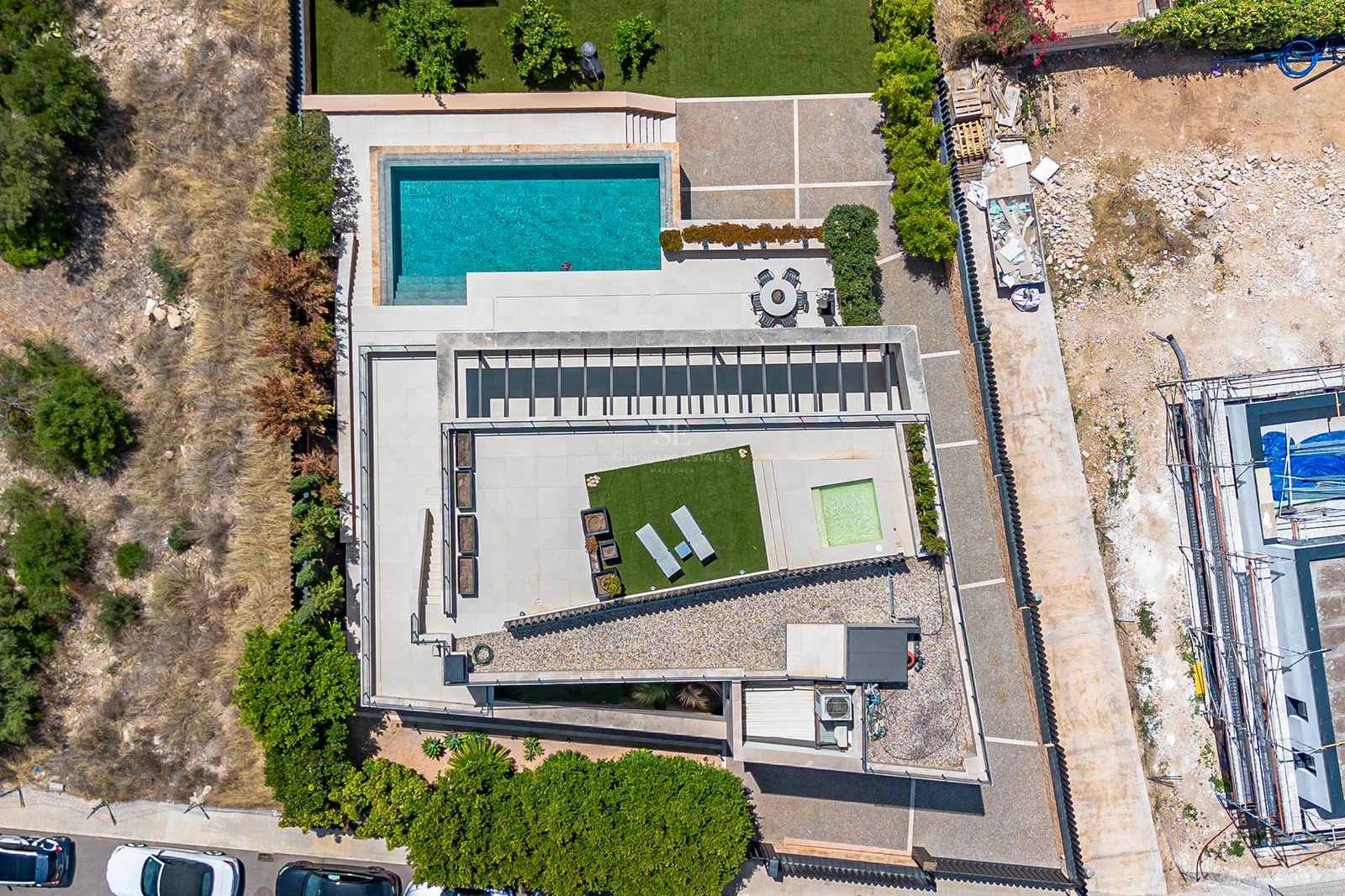 Top-down aerial view of a modern villa featuring a rectangular pool, multiple tiled terraces, and manicured lawns.