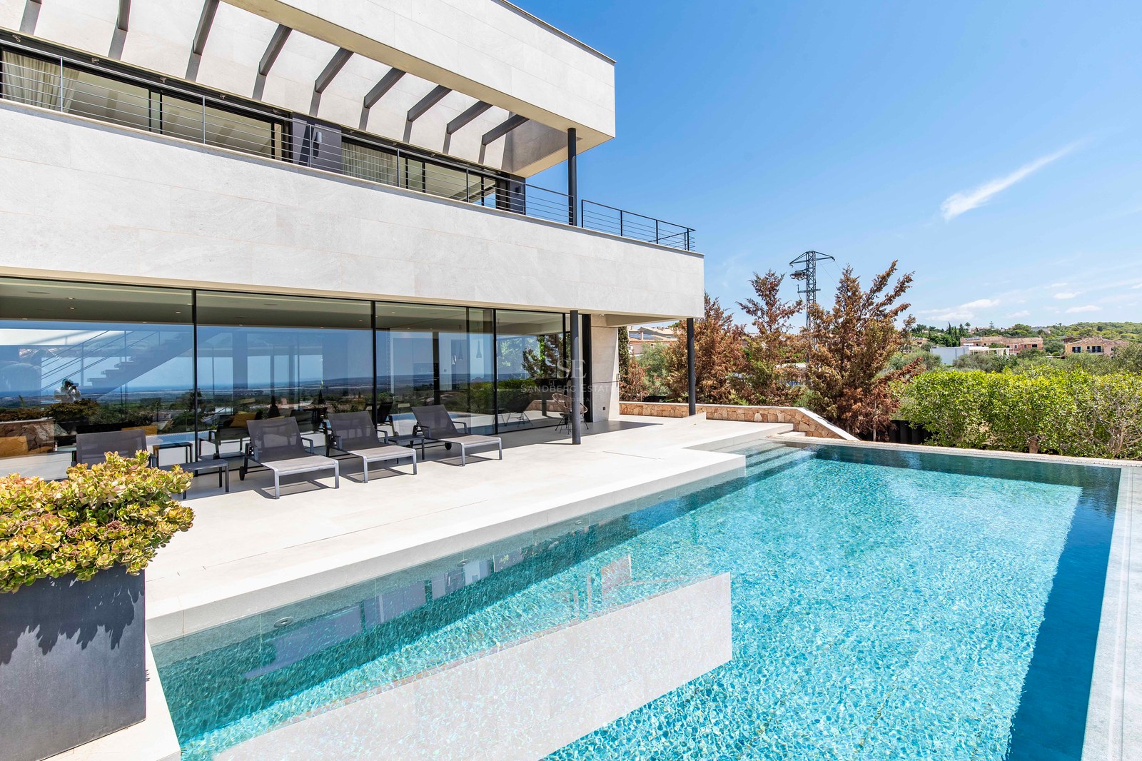 Modern luxury villa featuring an infinity pool, natural stone terrace, and floor-to-ceiling glass walls.