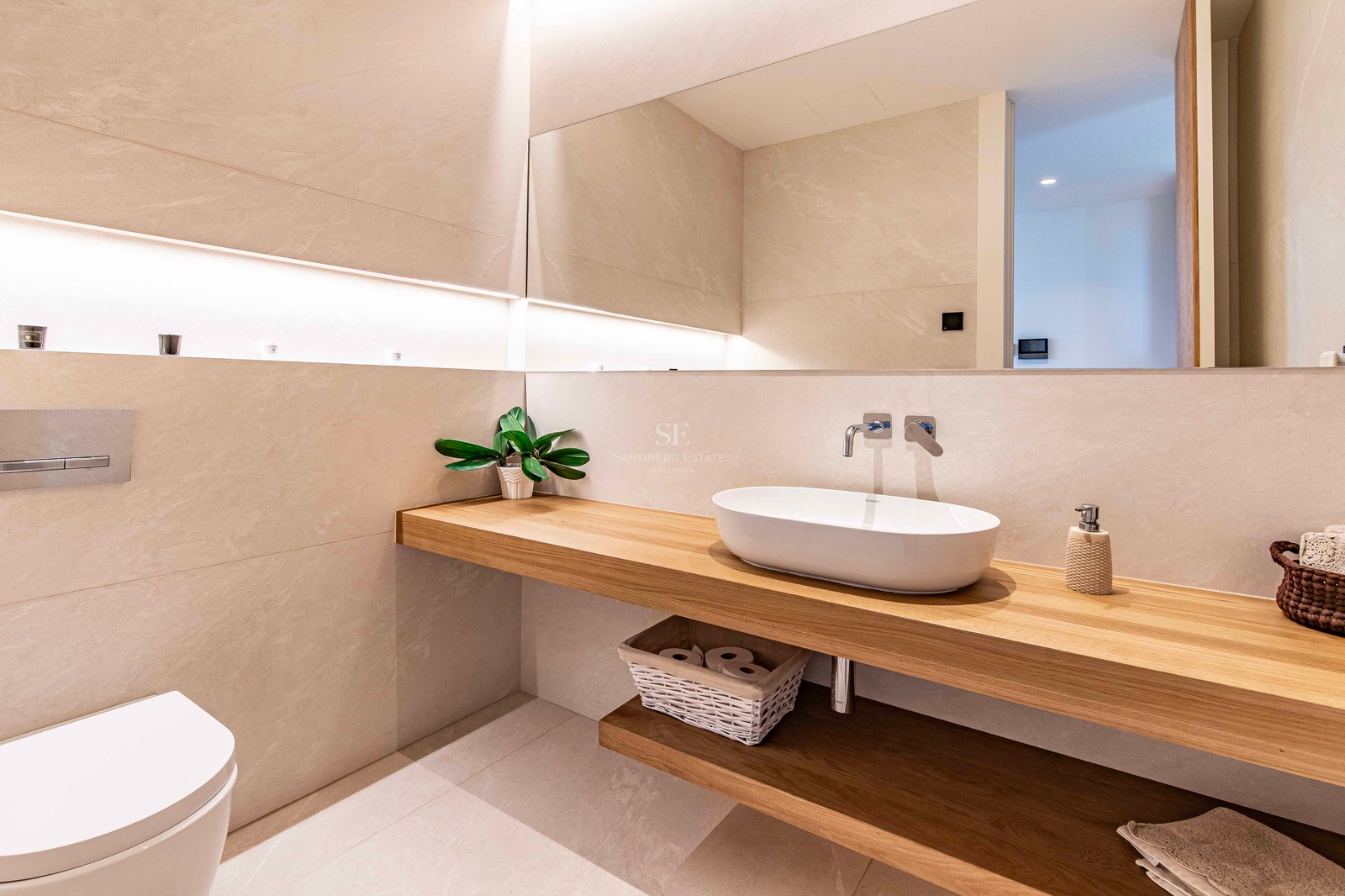Modern bathroom featuring a floating oak vanity, white vessel sink, large mirror, and warm recessed LED lighting.