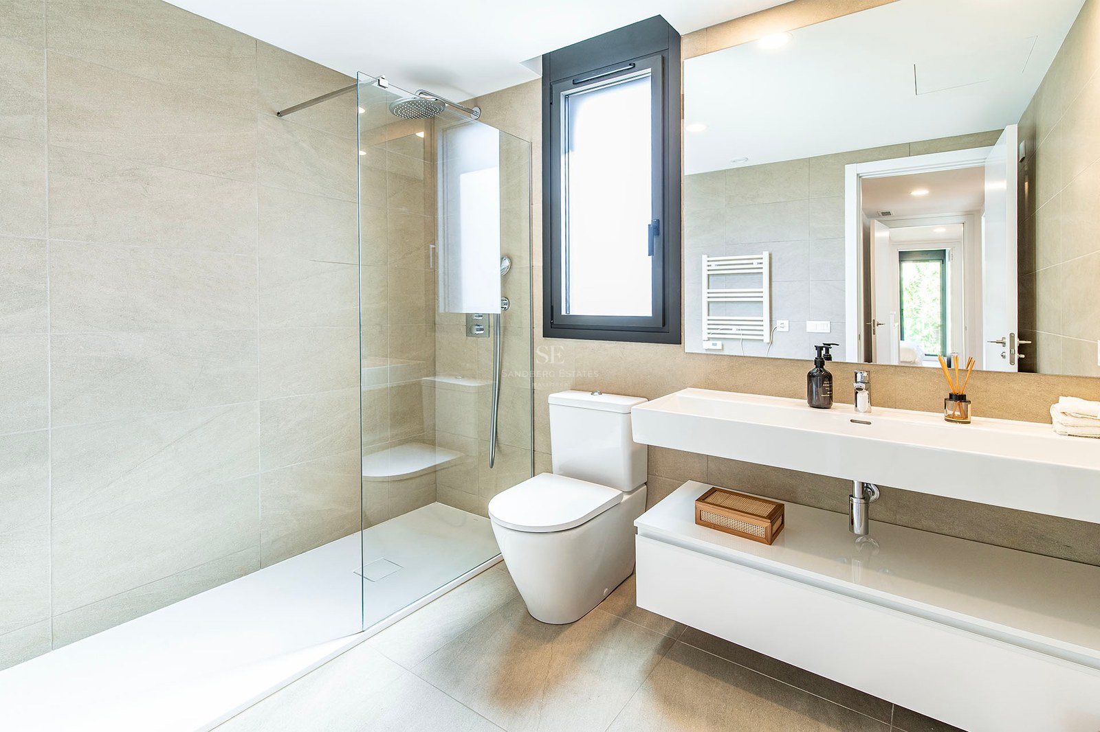 Cuarto de baño contemporáneo con azulejos beige, ducha con mampara de cristal y lavabo suspendido blanco.