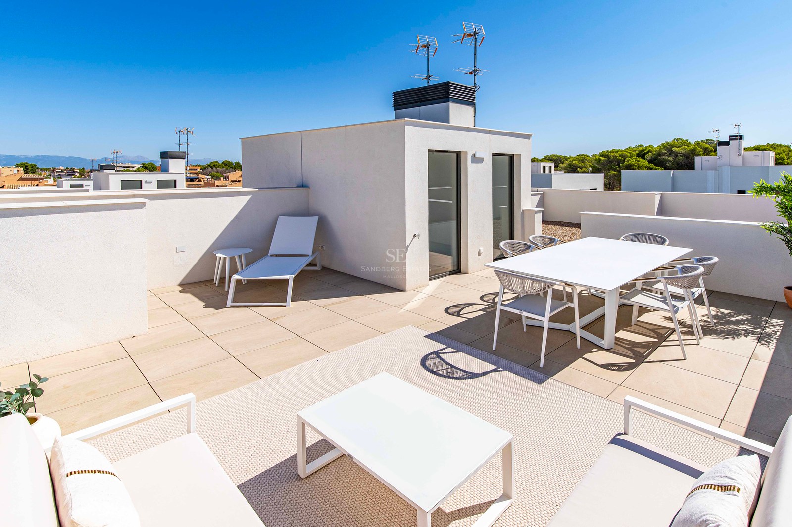 Moderne Dachterrasse mit weißen Outdoormöbeln, Esstisch für sechs Personen, Lounge-Set und Sonnenliege.