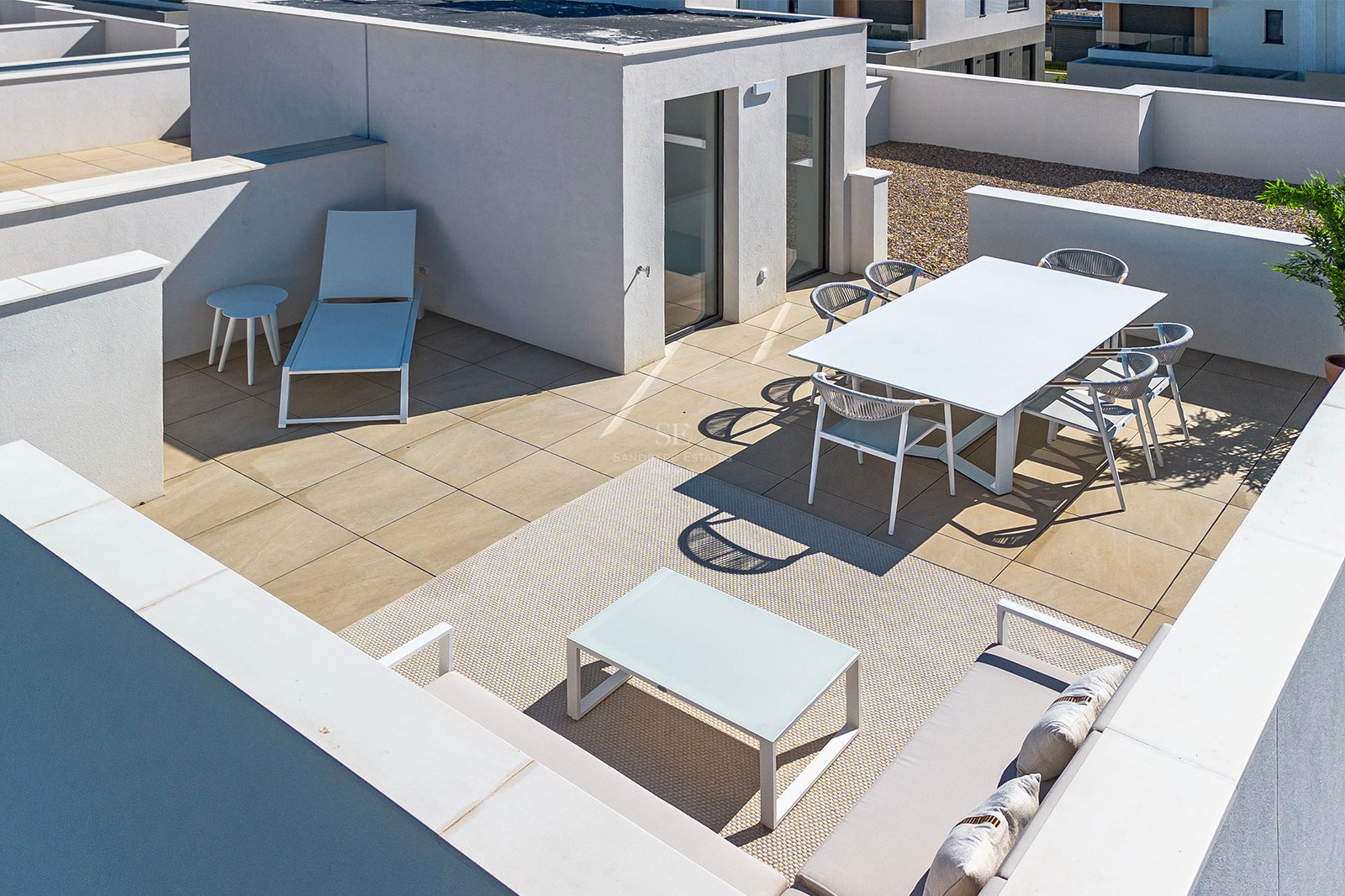 Erhöhte Ansicht einer weißen minimalistischen Dachterrasse mit Esstisch, Lounge-Möbeln und Sonnenliege.