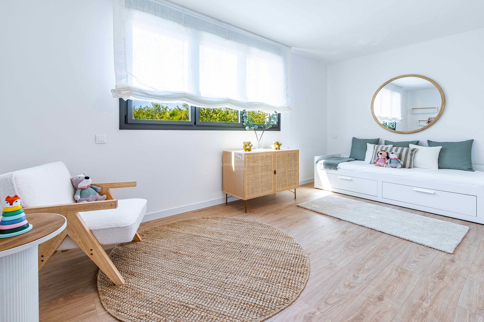 Modernes weißes Schlafzimmer mit Tagesbett, Juteteppich, Holzsessell und natürlichem Licht.