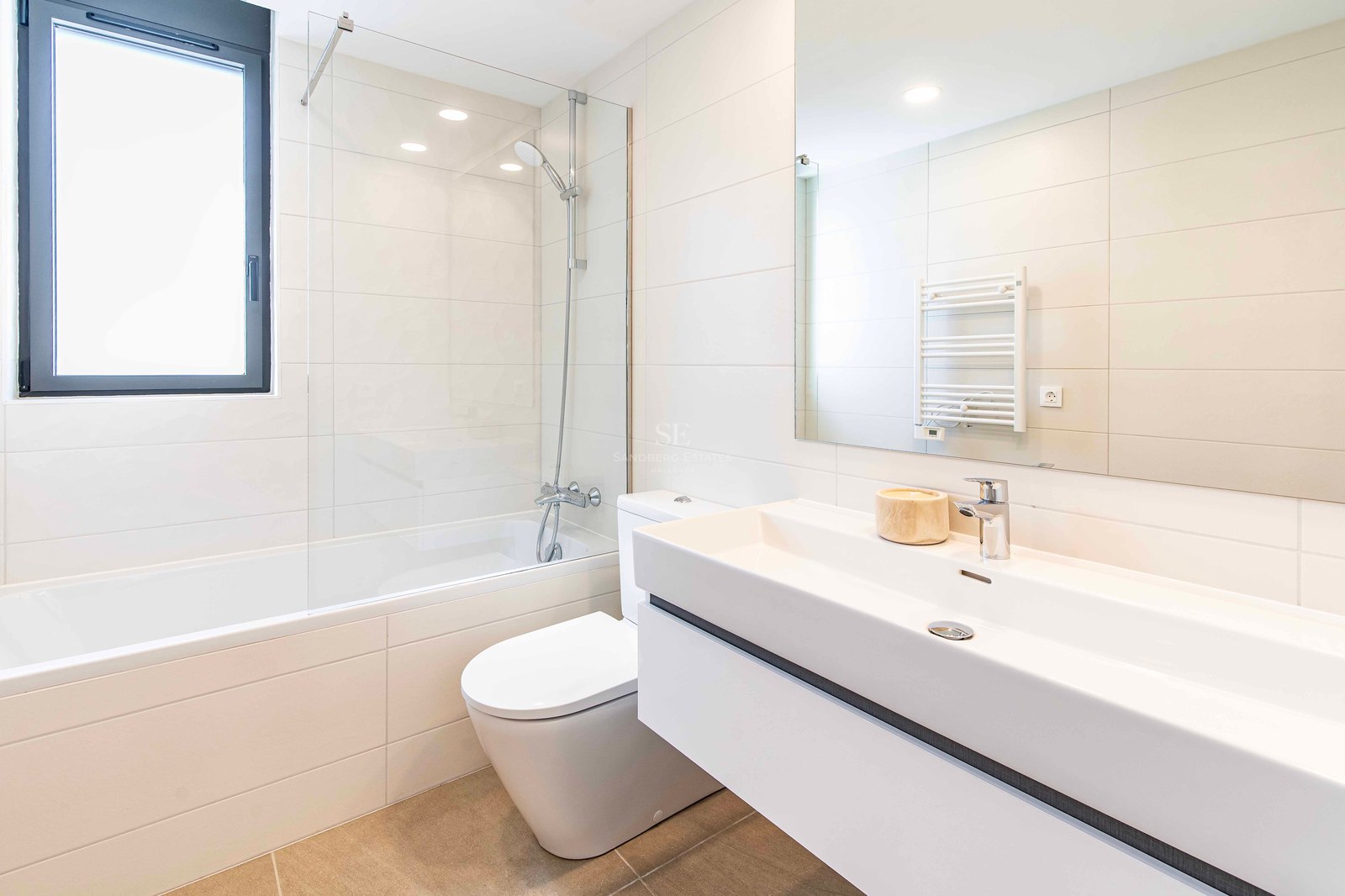 Zeitgenössisches Badezimmer mit Badewanne, Glasduschwand, Hänge-WC und breitem weißem Waschtisch.