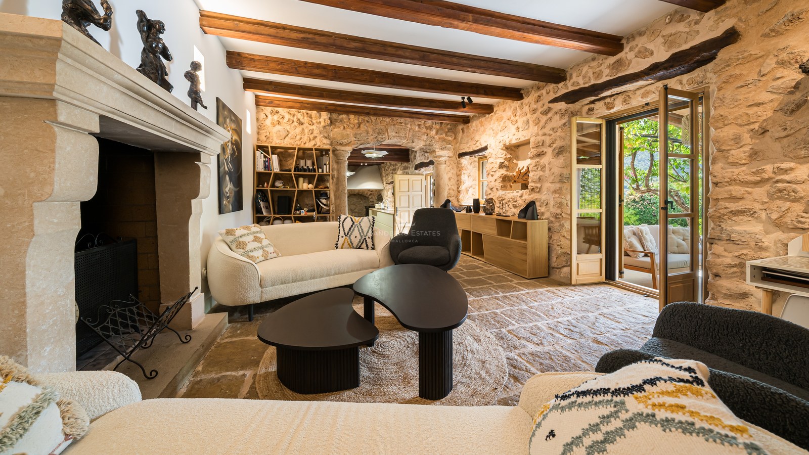Luxury living room interior featuring exposed stone walls, timber beams, a statement fireplace, and terrace access.