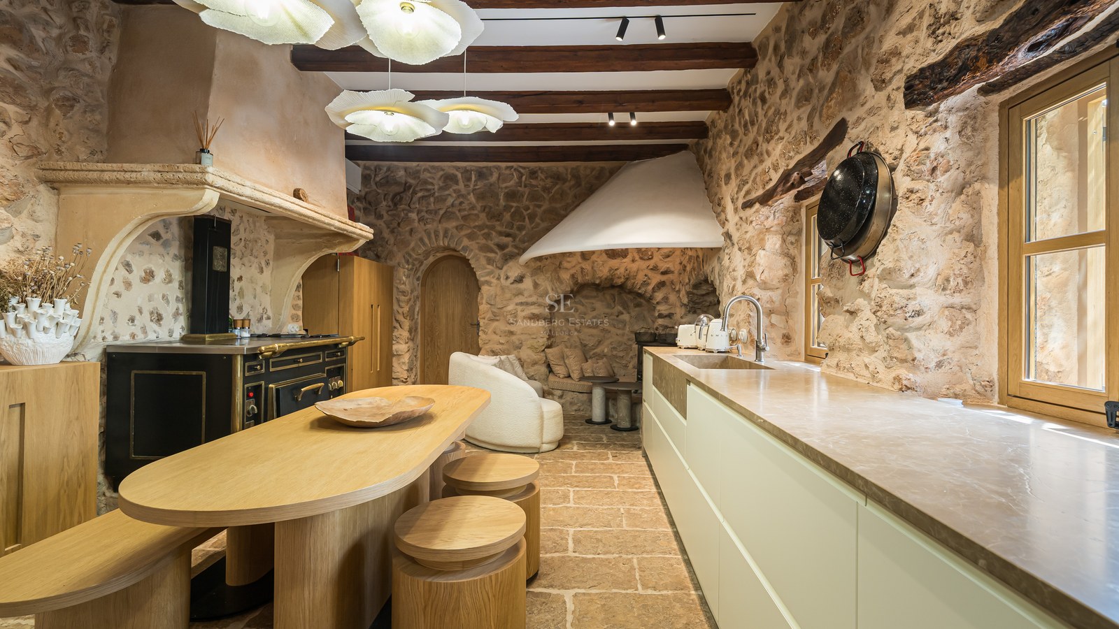 Luxury rustic kitchen with exposed stone walls, wooden beams, a custom oak island, and a vintage-style range cooker.