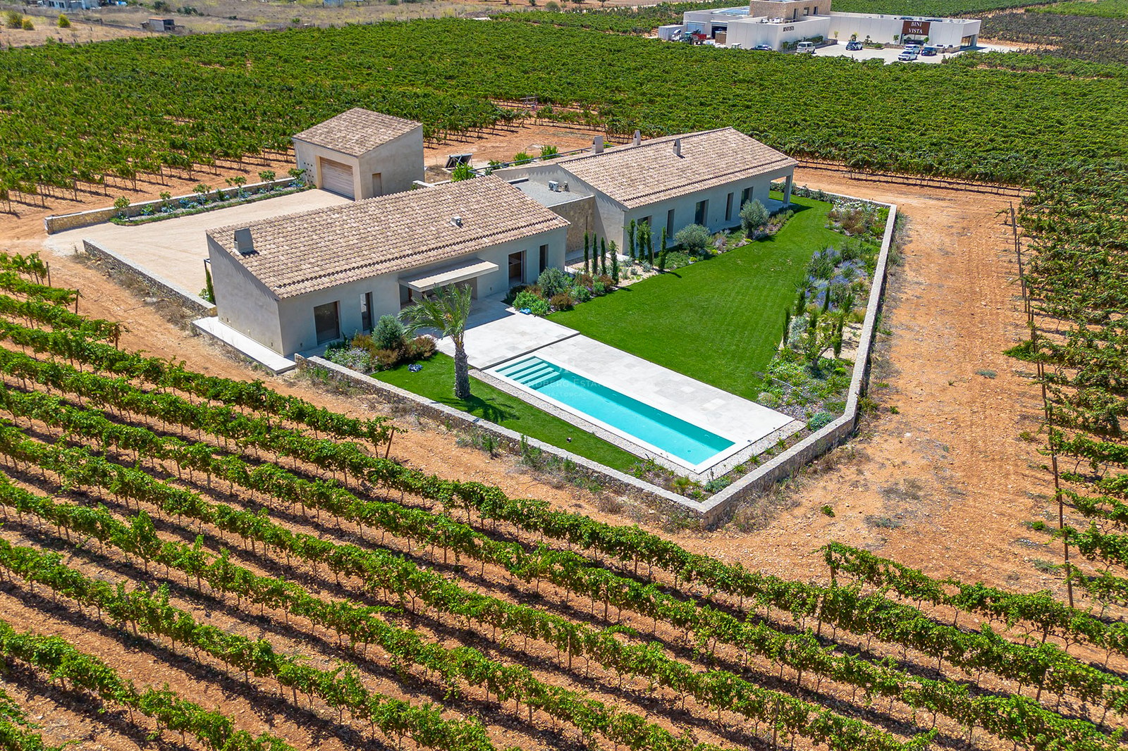 Vue aérienne d'une villa contemporaine avec piscine et toit en terre cuite, nichée au milieu de vignobles verdoyants.