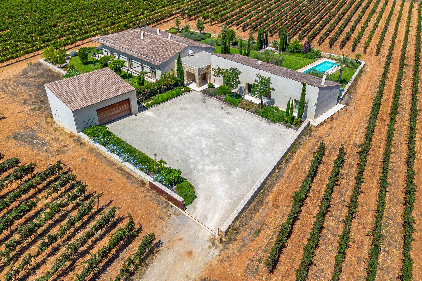 Vue aérienne d'une villa méditerranéenne avec toits en terre cuite, piscine privée et vastes vignobles.