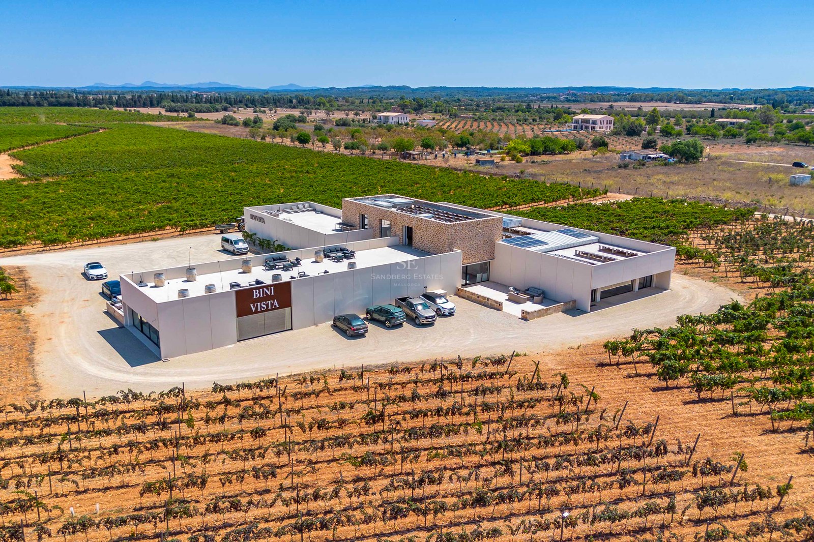 Vue par drone d'un domaine viticole moderne avec accents en pierre naturelle au milieu des vignes à Majorque.