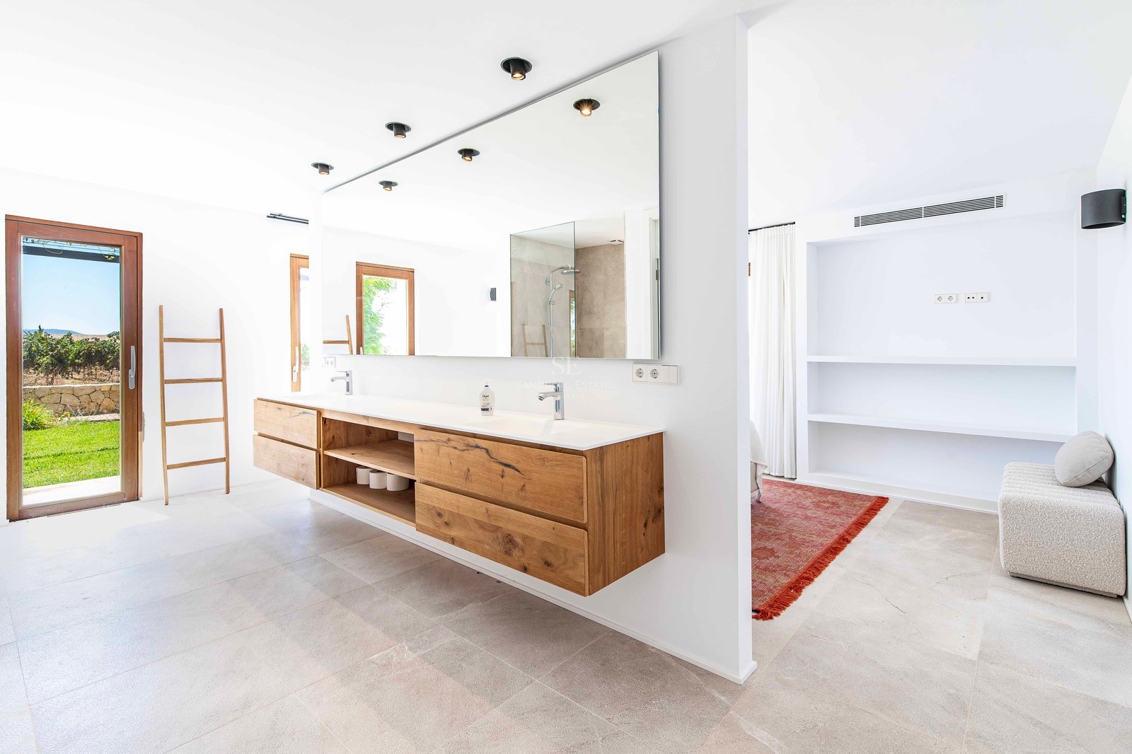 Grande salle de bain moderne avec meuble en chêne suspendu, grand miroir et accès direct au jardin.
