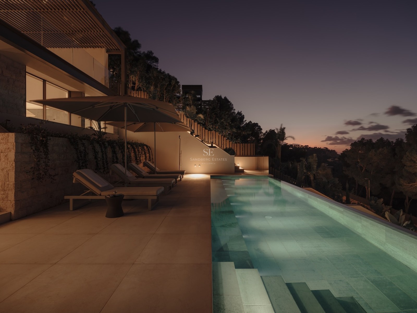 Piscina de lujo al anochecer con tumbonas y sombrillas en una terraza de piedra con vistas a la naturaleza.