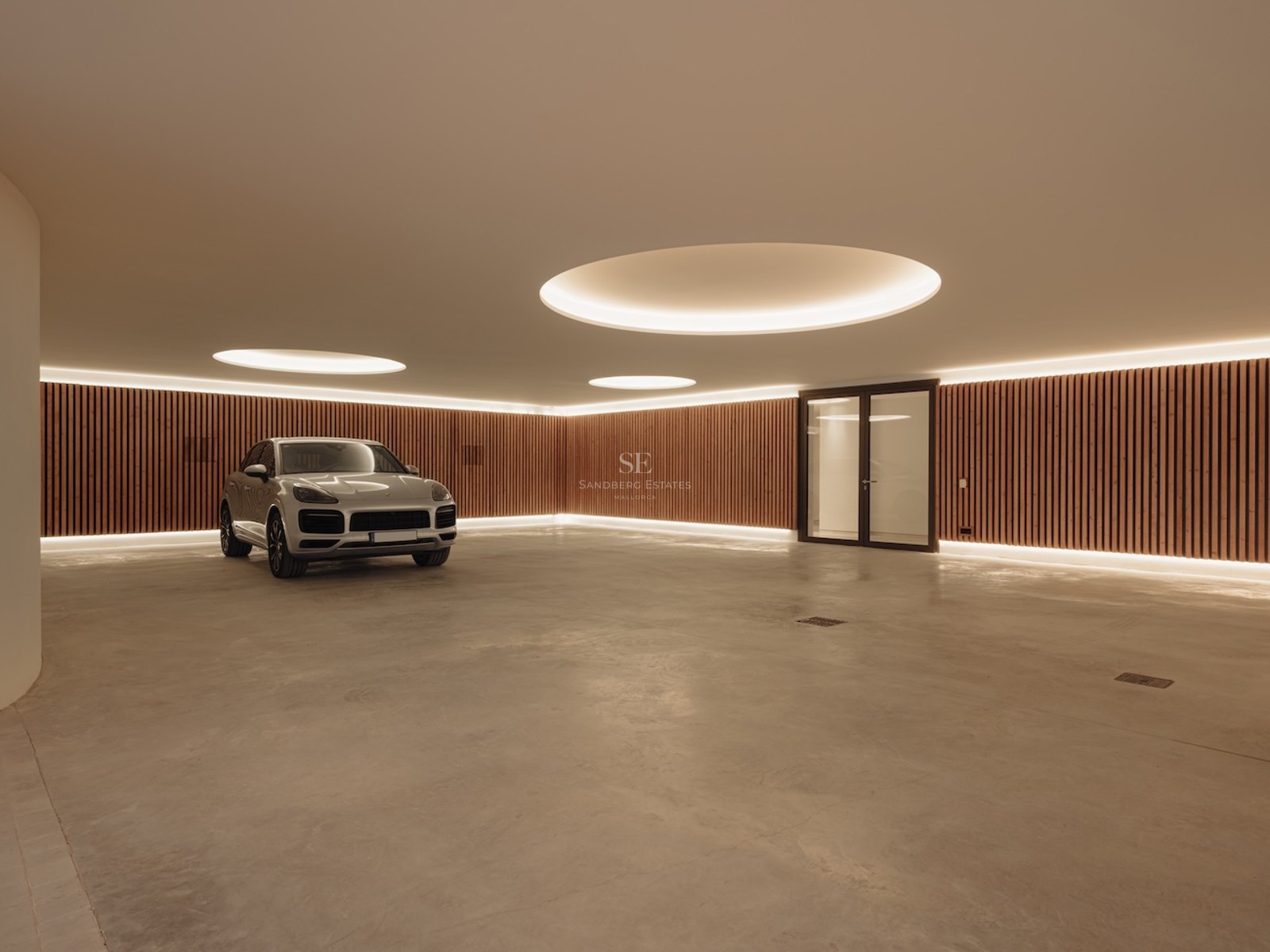 Garaje subterráneo moderno con suelos de hormigón pulido, paredes de madera y luces circulares empotradas.