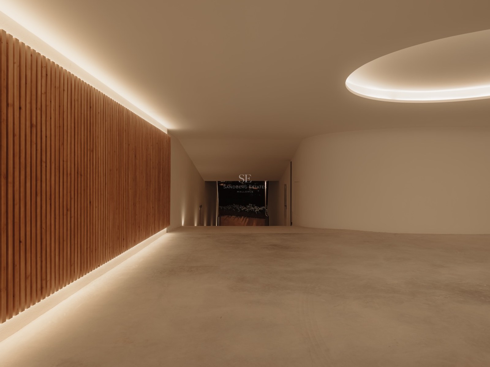 Rampa de garaje minimalista con paredes de hormigón, paneles de listones de madera e iluminación LED indirecta.