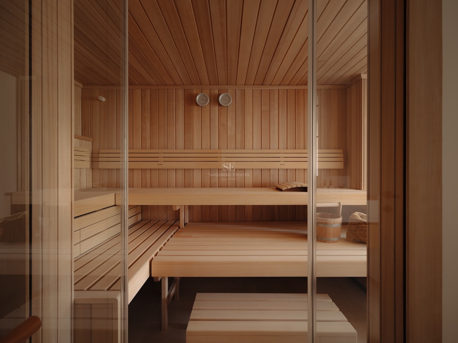 Interior de una sauna moderna de madera con asientos a varios niveles y puerta de entrada de cristal.