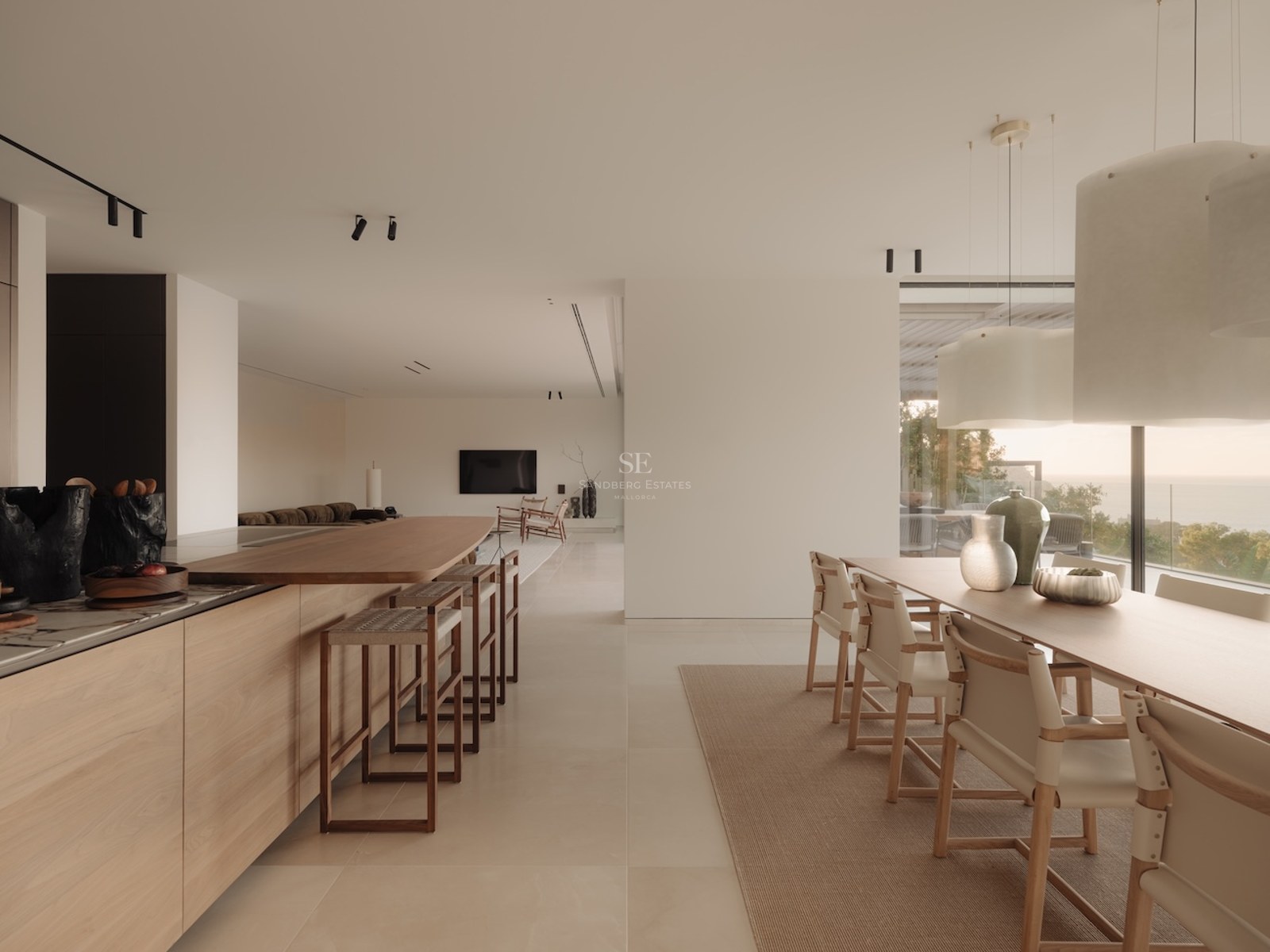 Cocina moderna de concepto abierto con muebles de roble, isla de mármol y grandes ventanales con vistas al mar.