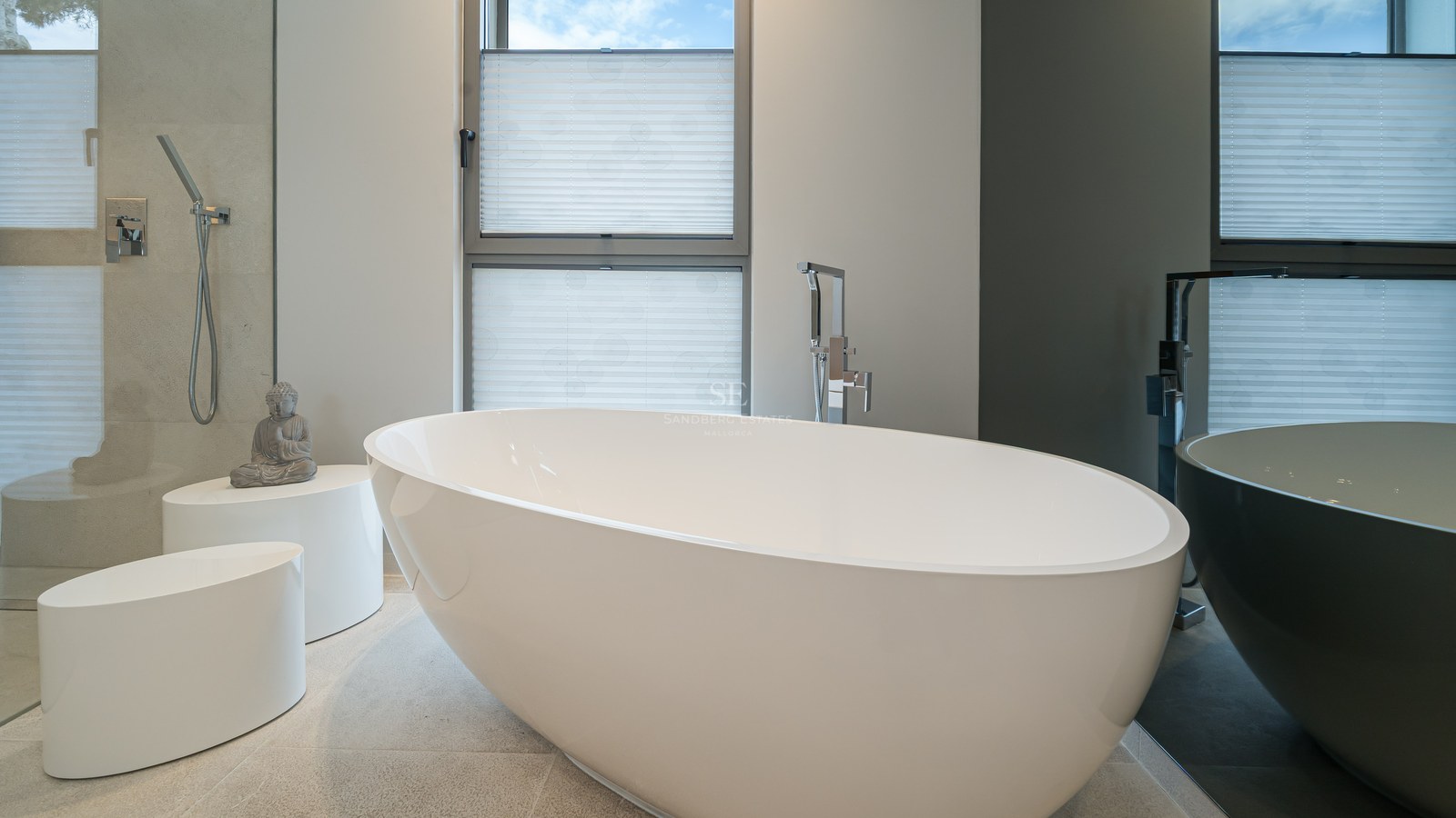 Minimalist bathroom featuring a white freestanding oval bathtub, natural stone flooring, and a walk-in shower.