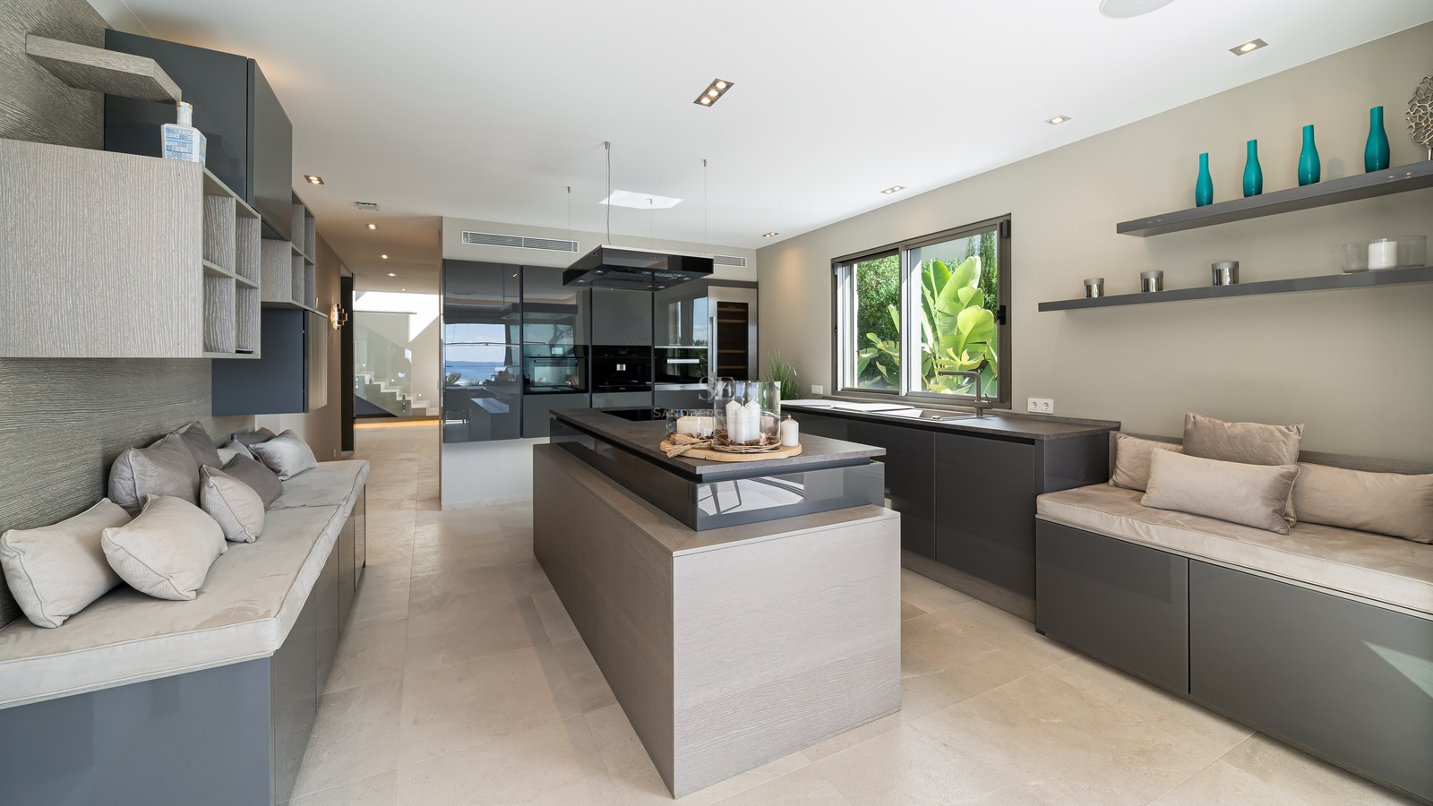 Modern kitchen featuring anthracite cabinetry, wood-textured island, and integrated lounge seating.