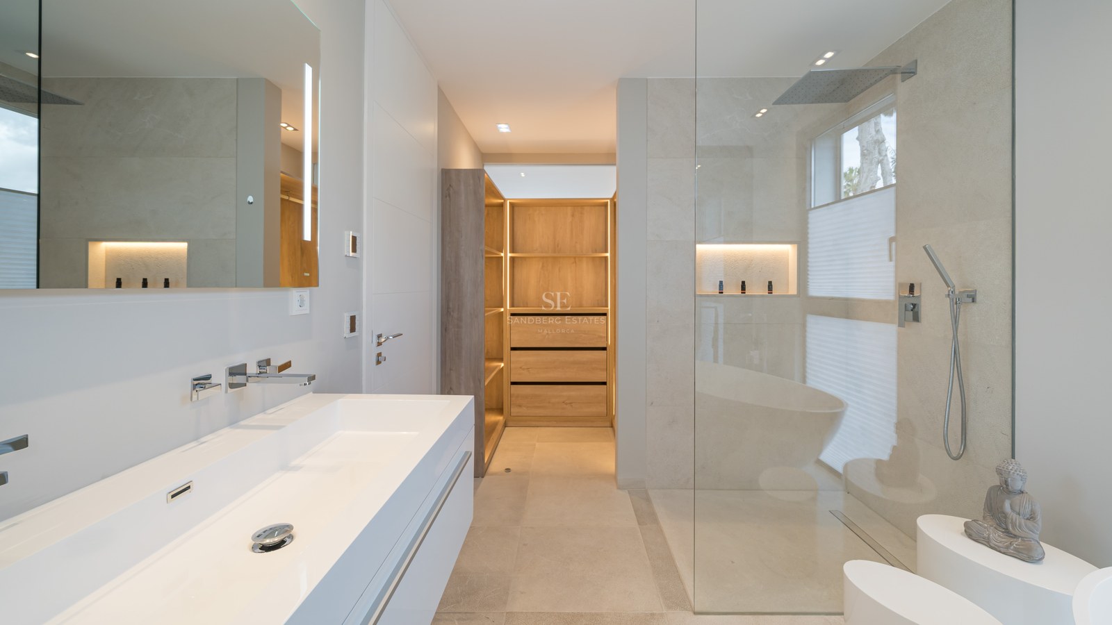 High-end modern bathroom featuring a white double vanity, glass rain shower, and an illuminated wooden walk-in closet.