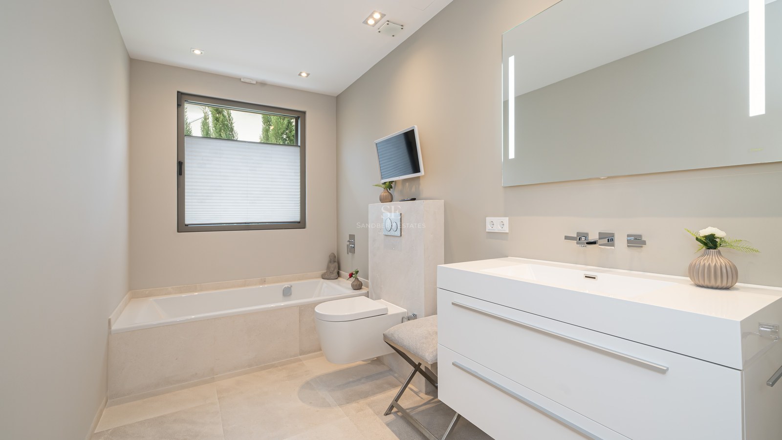 Minimalist bathroom featuring a white vanity, a built-in bathtub, a wall-hung toilet, and a wall-mounted television.