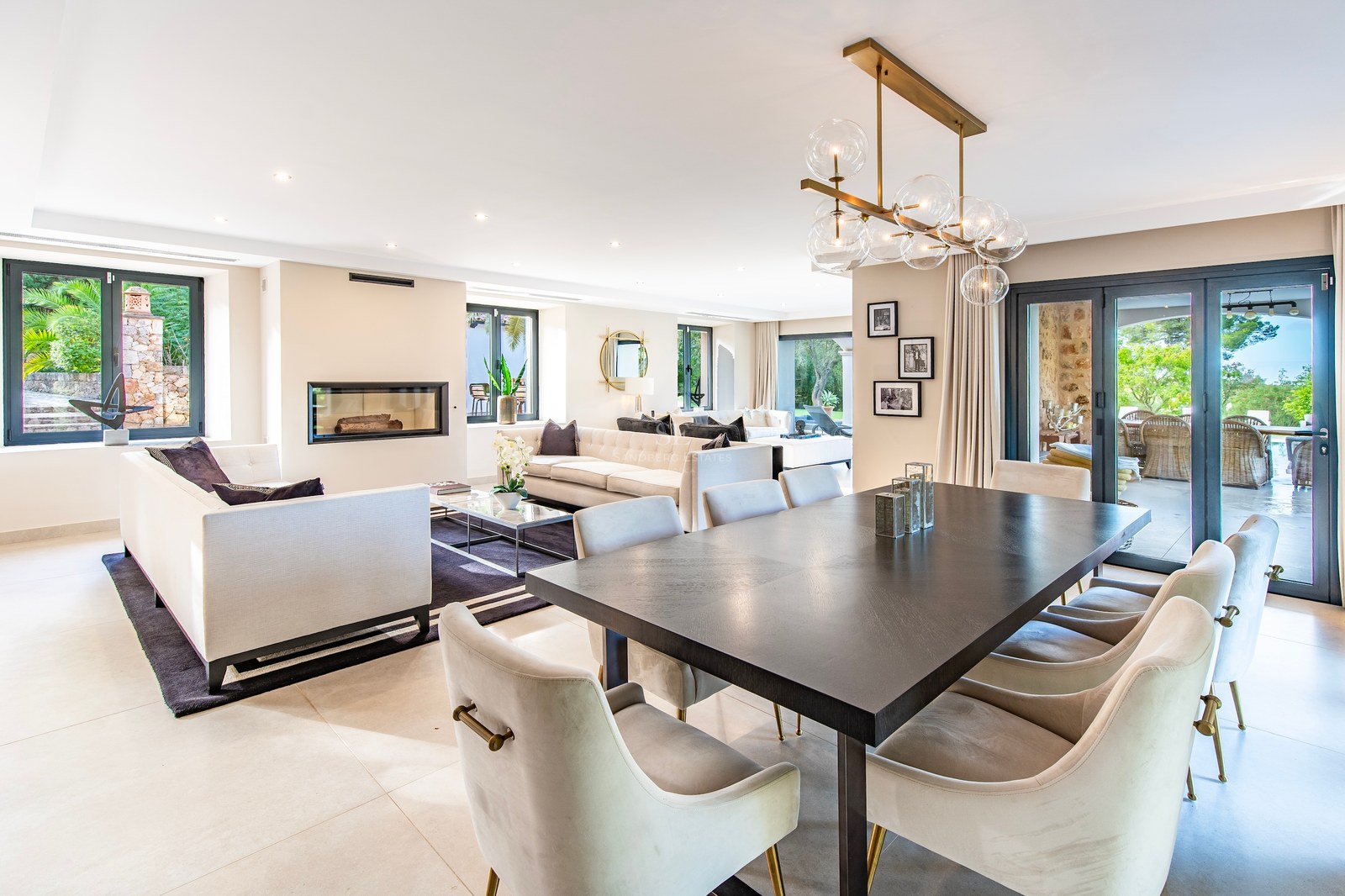 Salón y comedor de diseño contemporáneo con mesa de madera oscura, sofás en crema y chimenea moderna integrada.