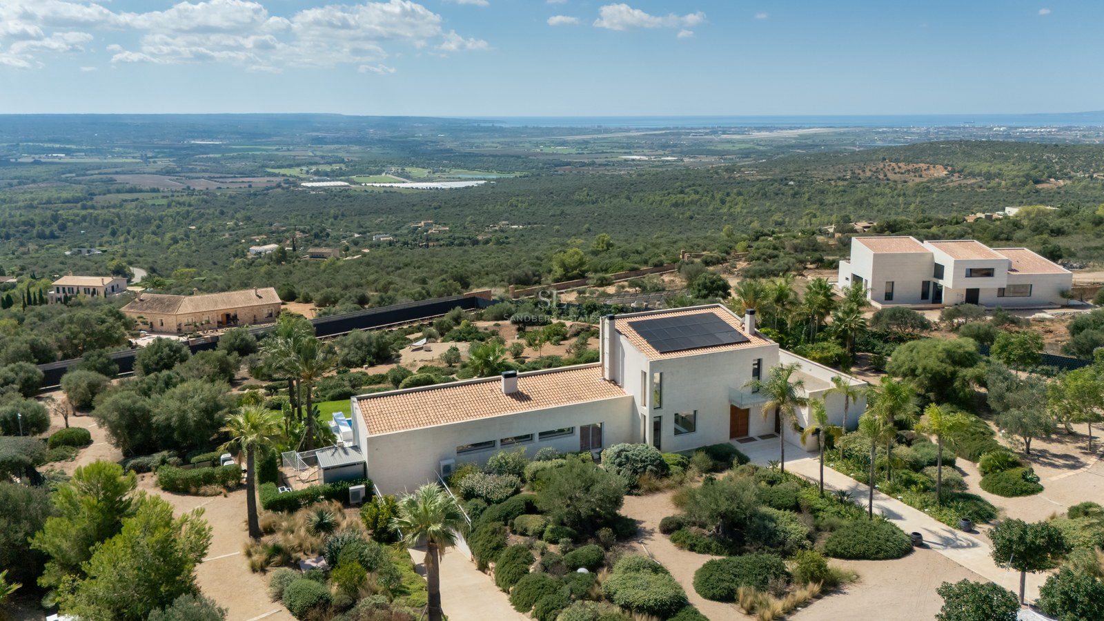Vista de piscina infinita y jardín exuberante. Arquitectura moderna con amplios ventanales y terraza amueblada. Diseño elegante y sofisticado.