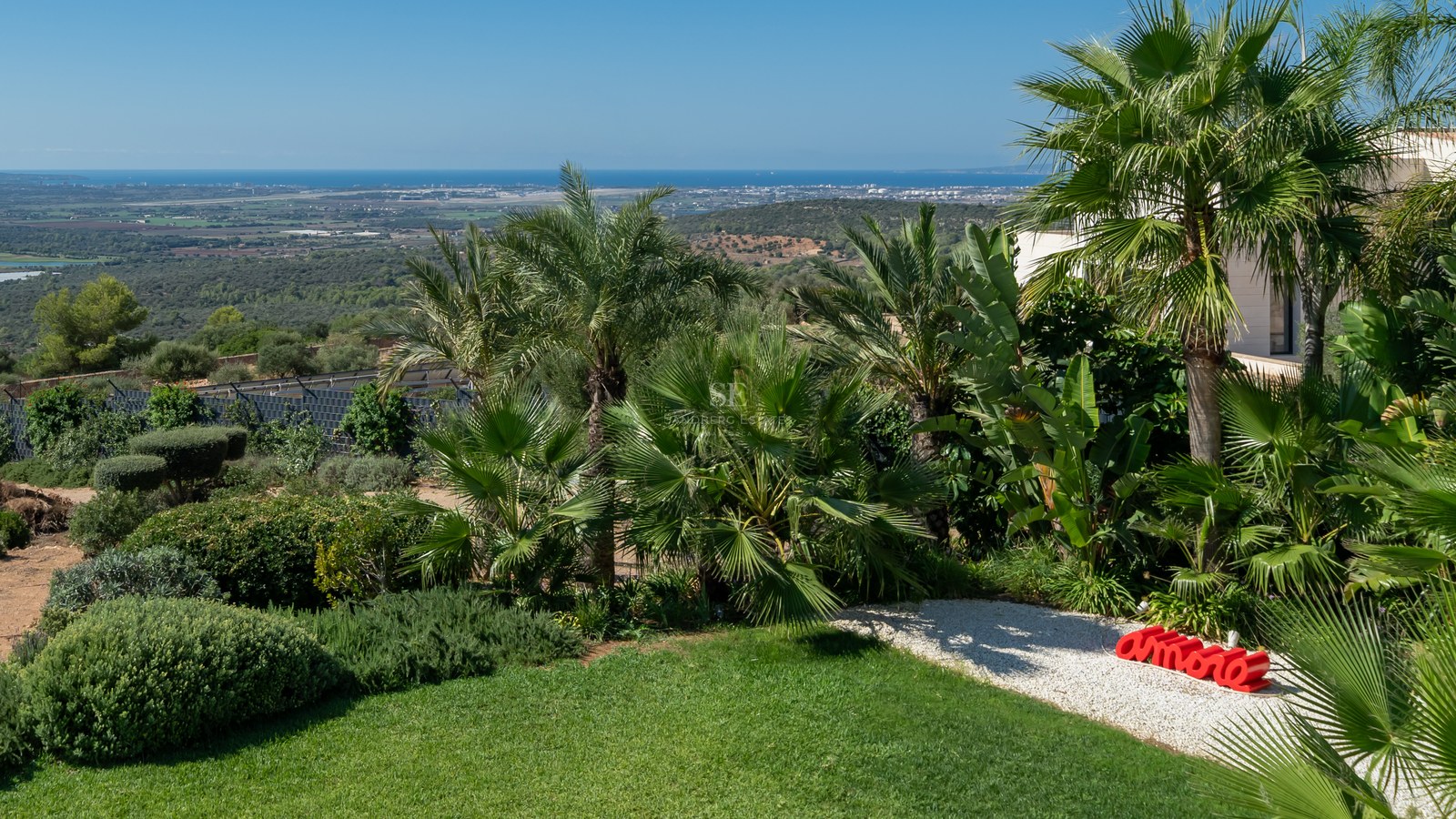 Vista exterior de villa moderna con piscina infinita, jardín exuberante y amplias terrazas. Arquitectura minimalista y diseño elegante.