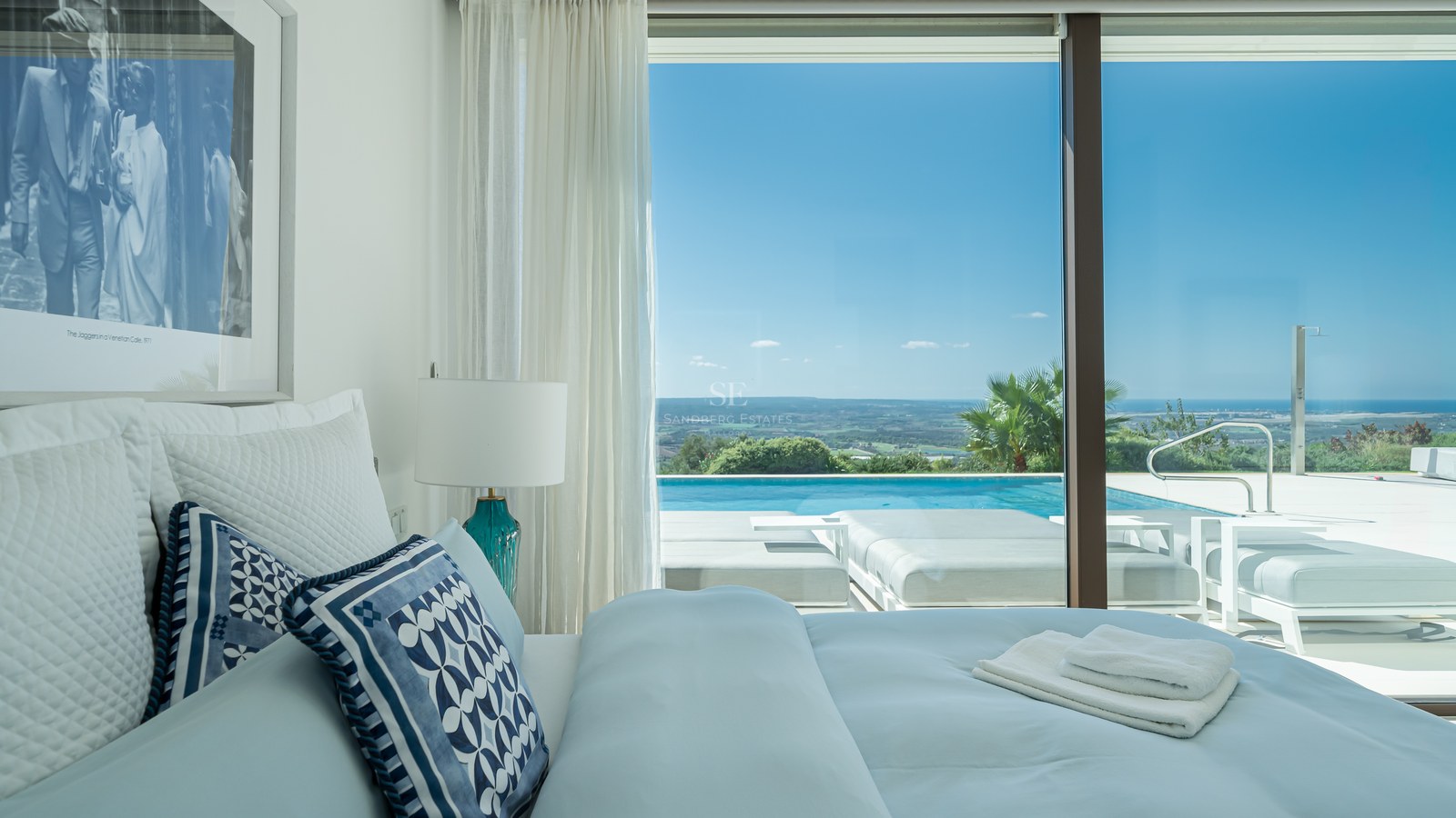 Vista de una piscina moderna rodeada de vegetación exuberante y una casa con grandes ventanales y diseño minimalista.