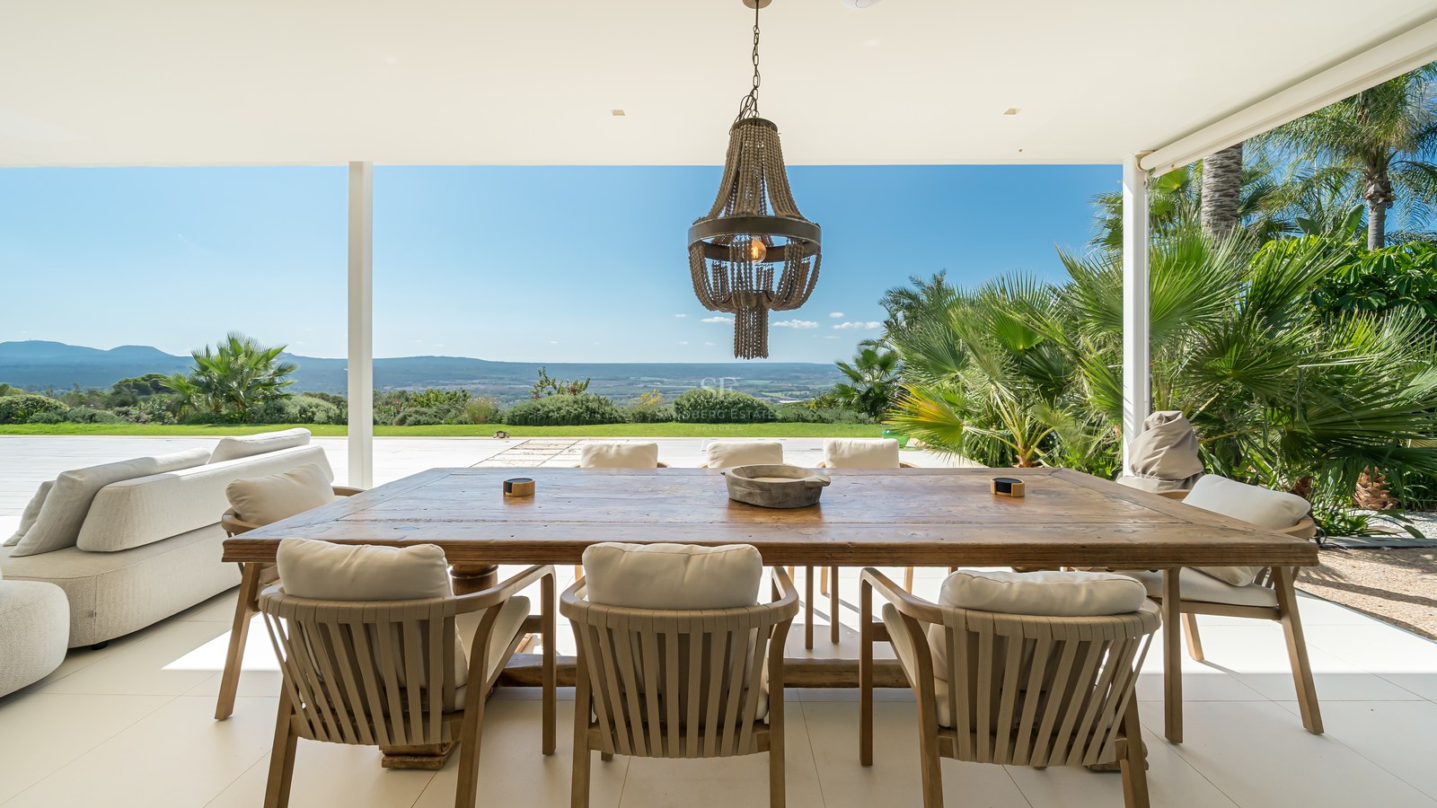 Vista de una piscina moderna rodeada de vegetación exuberante y una casa con grandes ventanales. Diseño minimalista.