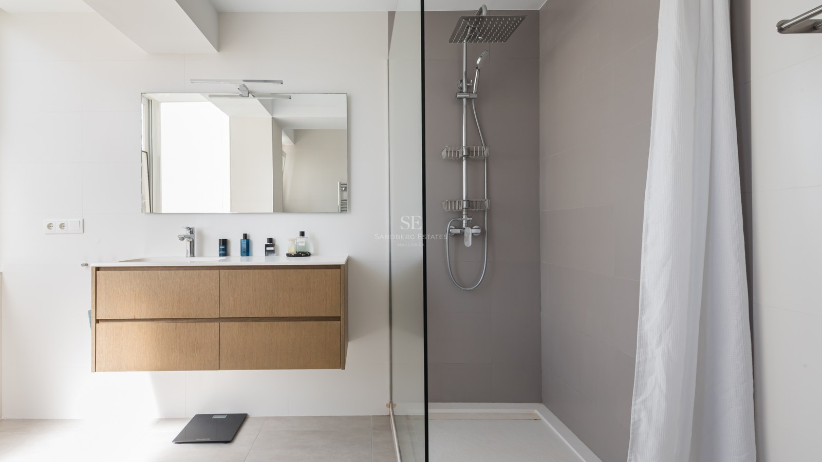 Utsikt över en modern villa med infinitypool, solstolar och en frodig trädgård. Minimalistisk arkitektur med stora fönsterpartier.
