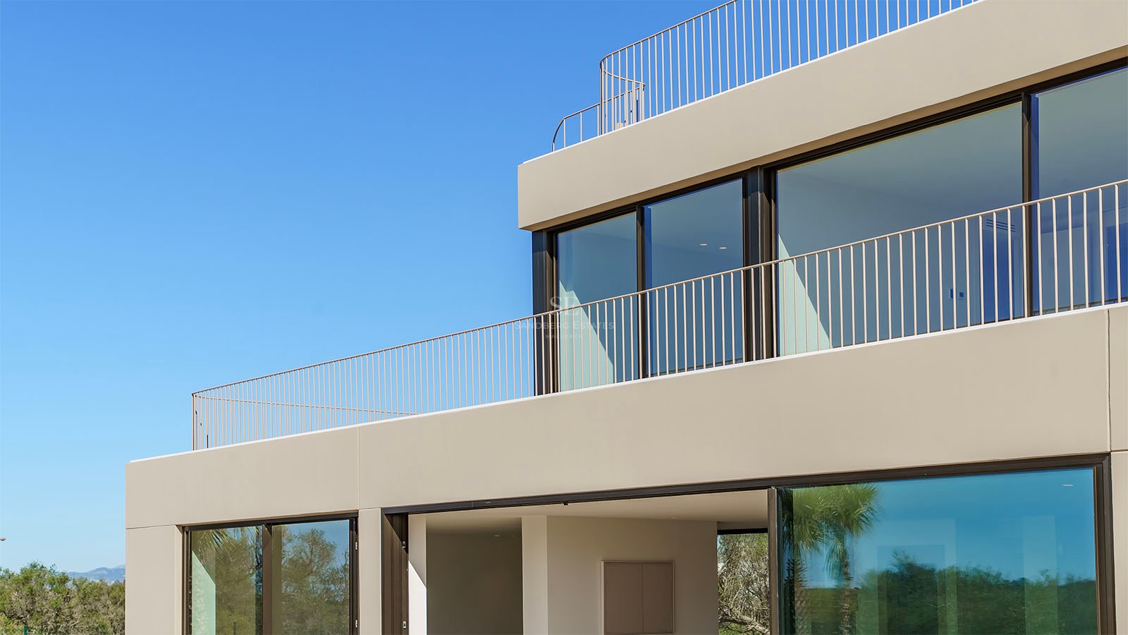 Façade d'une villa contemporaine beige avec de grandes fenêtres en verre et des garde-corps en métal minimalistes.