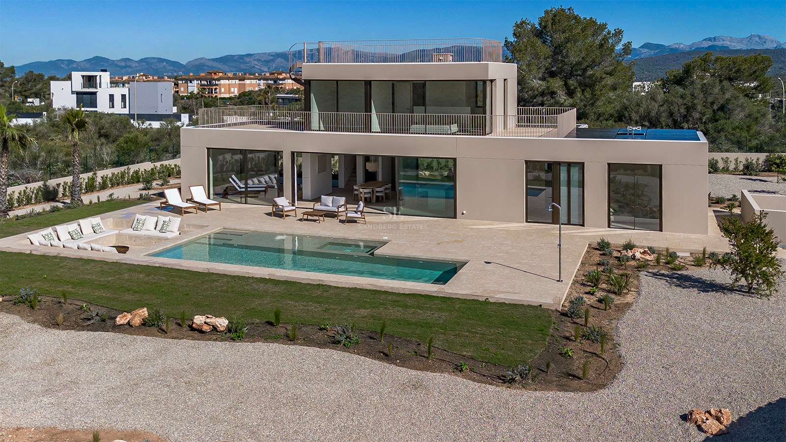 Façade d'une villa contemporaine avec piscine rectangulaire, grande terrasse en pierre et baies vitrées.