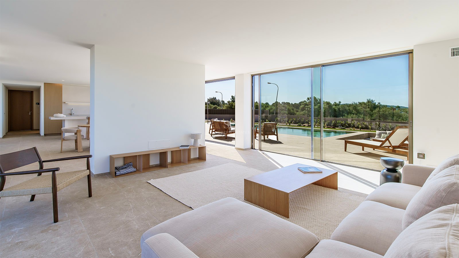 Salon lumineux minimaliste avec baies vitrées ouvrant sur une terrasse ensoleillée et une piscine.